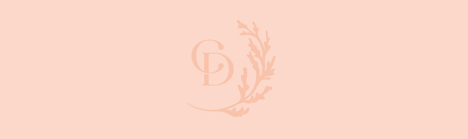 The image shows a close-up view of a pink fabric with a subtle texture, featuring a rectangular emblem on the left side, which appears to be a stylized letter  D  within a border that may suggest a shield or crest design.