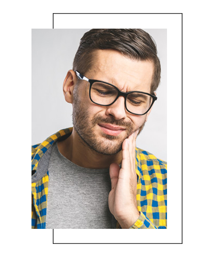 A man with glasses and a beard, looking distressed or anxious, holding his face with one hand.