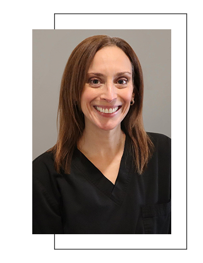 The image shows a woman wearing a black shirt, smiling at the camera, with short hair, posing for a professional headshot.
