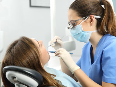 The image features a dental hygienist performing oral care on a patient while wearing protective gear.