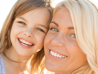 A mother and daughter smiling at the camera.