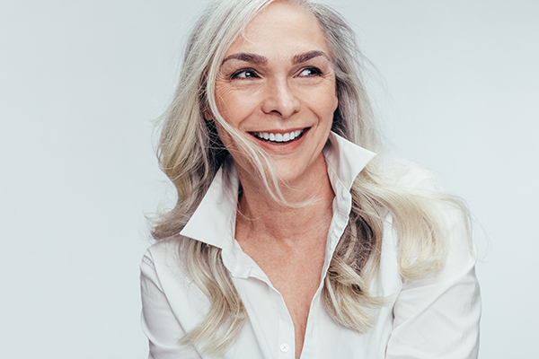 The image features a person with short hair smiling at the camera, wearing a white top.