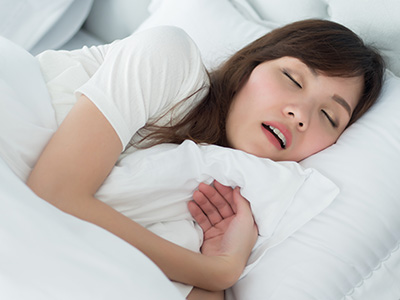 Woman sleeping peacefully on bed with white sheets.